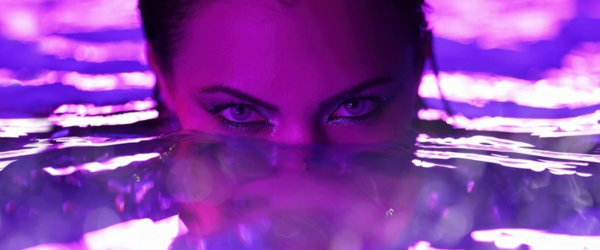 Beautiful first time swinging wife posing in pool water under neon color light.
