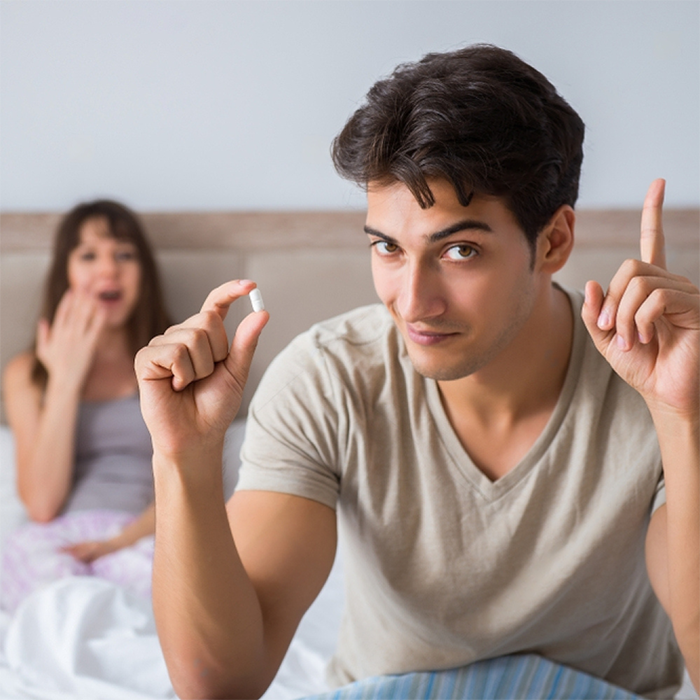 Husband and wife in bed about to ingest a Stamina for Men instant erection pill